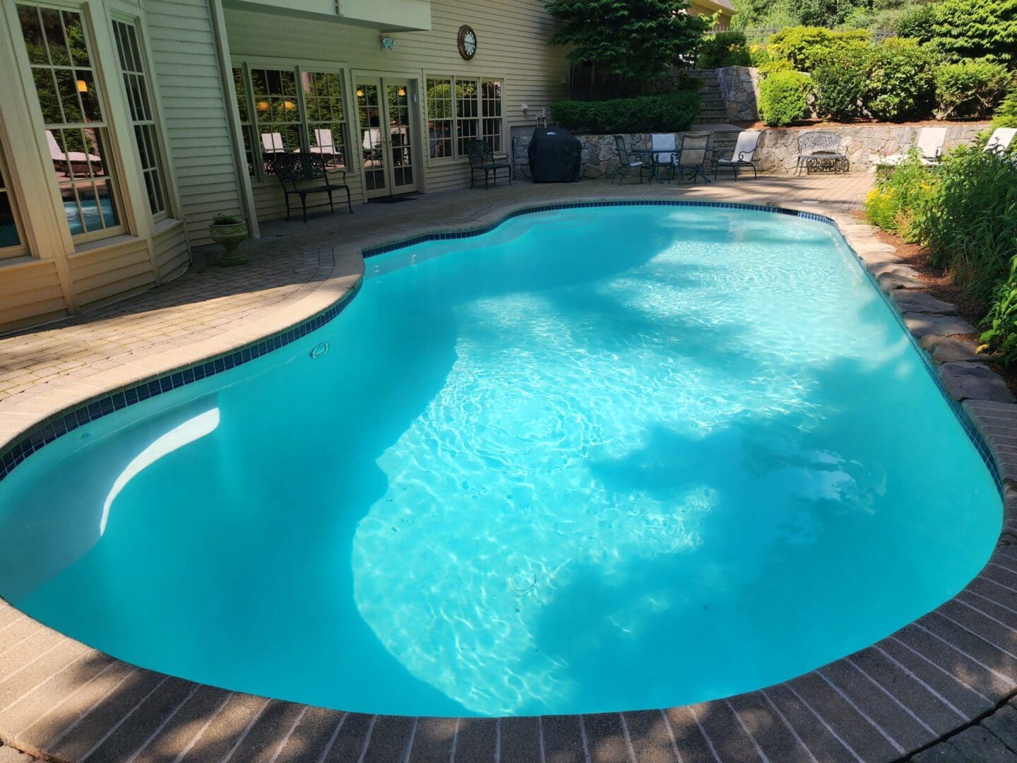 A pool with a brick deck and tile floor.