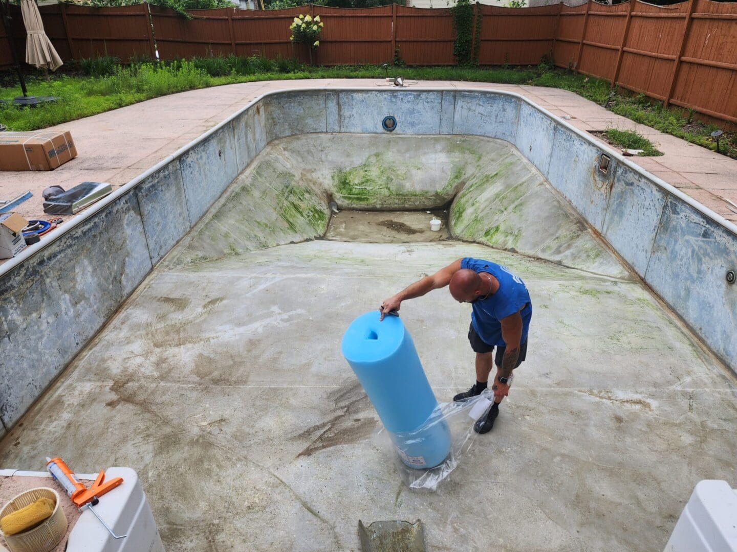 A man in blue shirt standing next to pool.