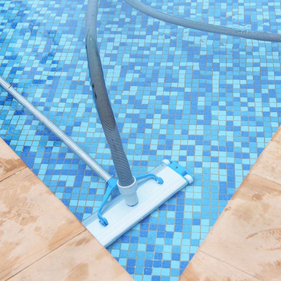 A pool cleaning tool is on the side of the pool.