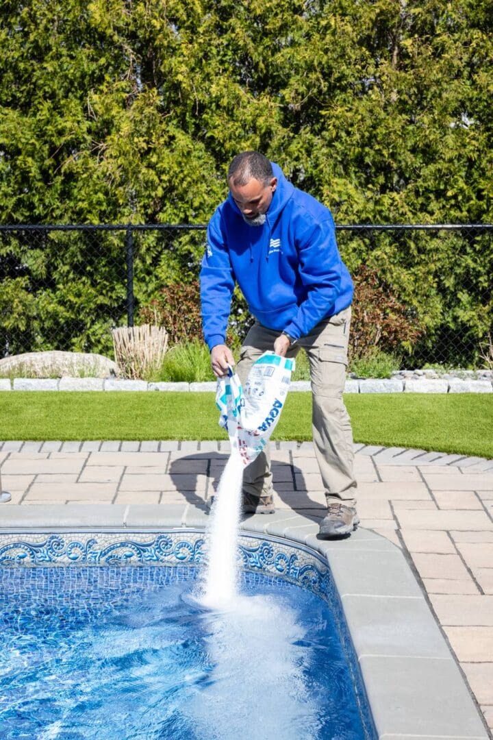 A man in blue jacket using hose to spray water.