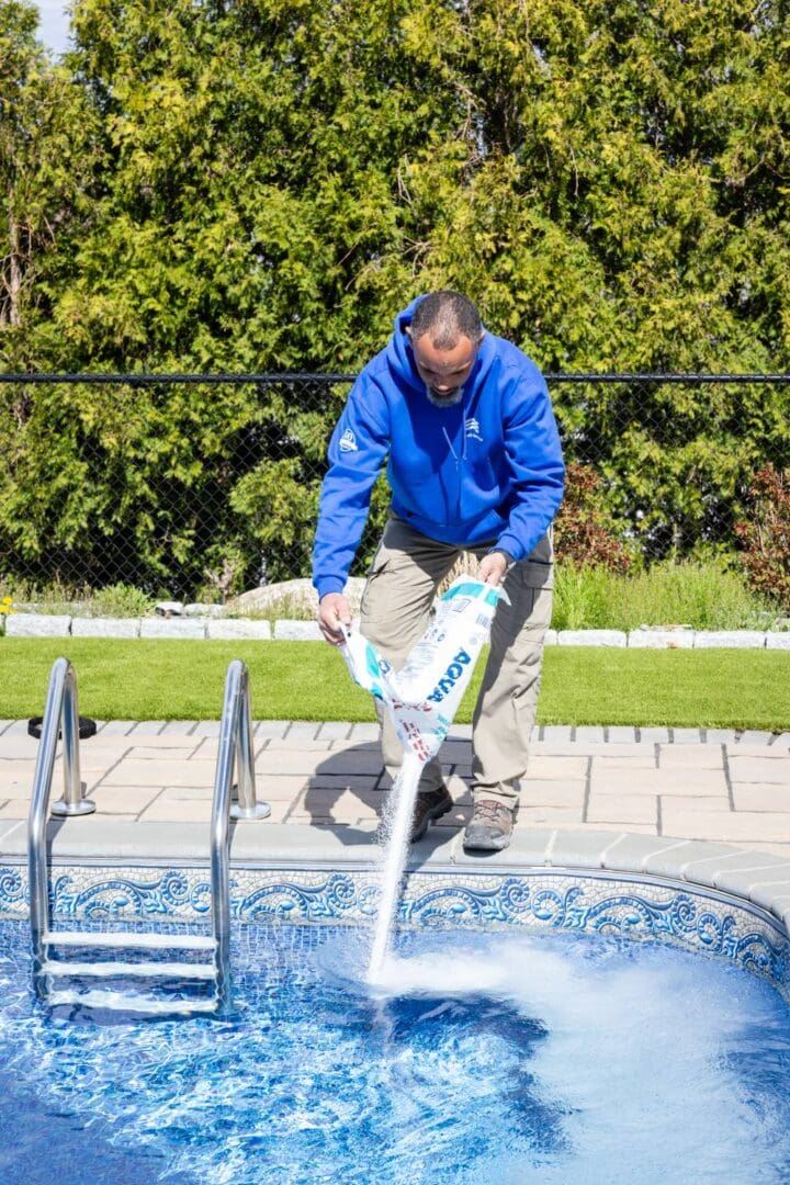 A man is spraying water into the pool.
