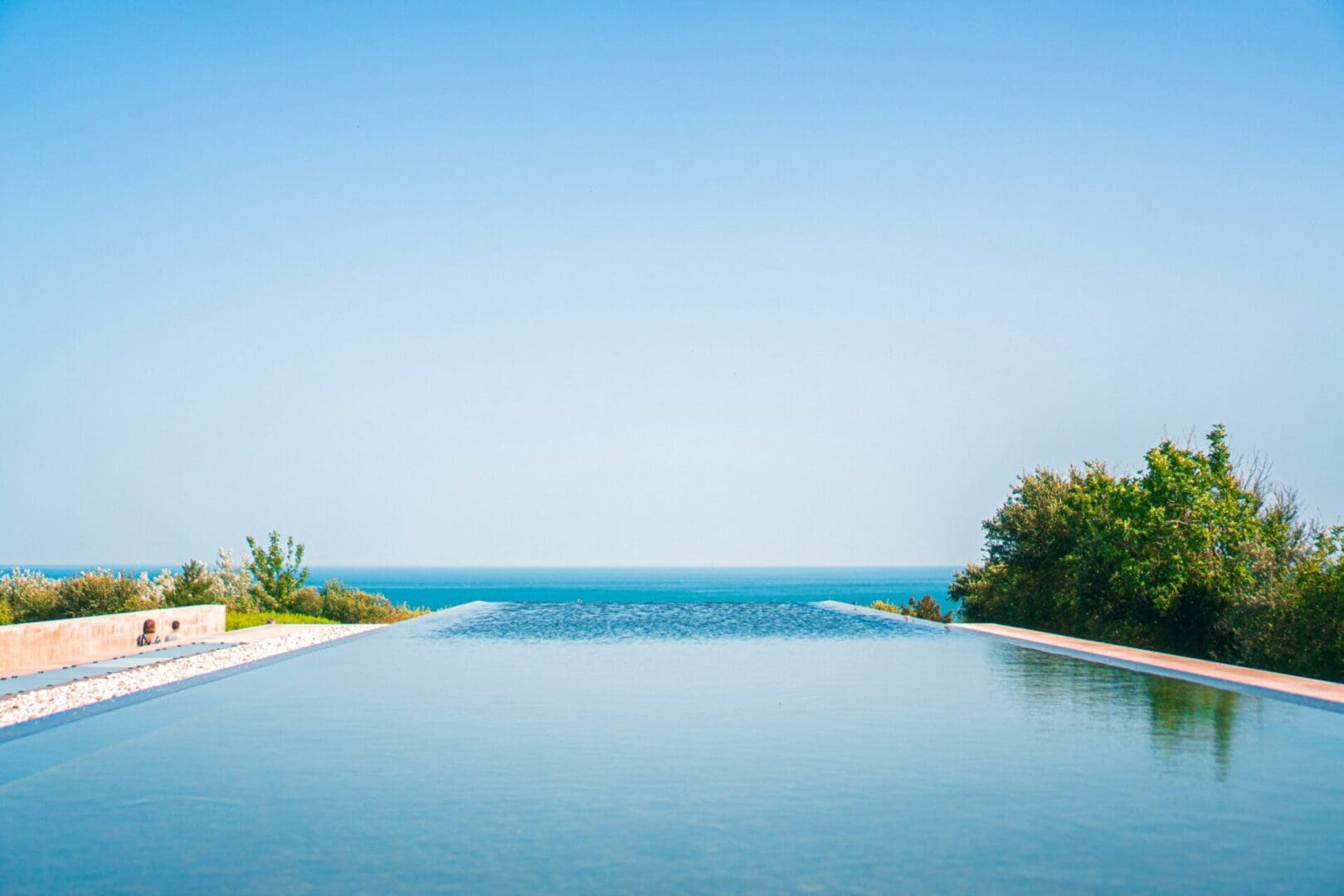 A pool with an ocean view and trees in the background.