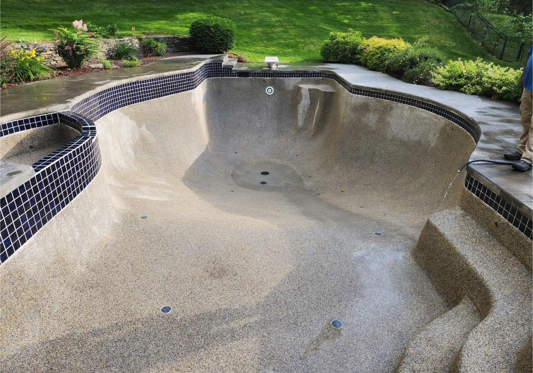 A concrete pool with a wall and bench