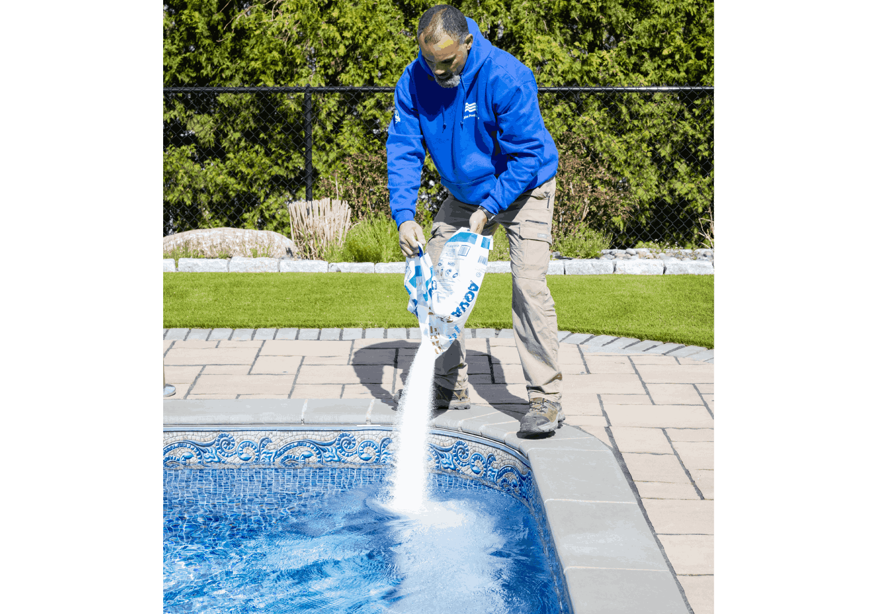 A man in blue jacket pouring water into pool.